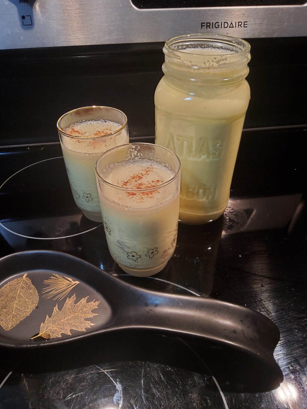 Photo of two glasses of eggnog with a full mason jar of eggnog beside them. 